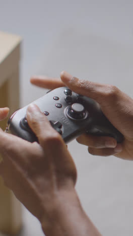 Vertical-Video-Close-Up-Of-Man-Holding-Controller-Sitting-On-Sofa-At-Home-Gaming-Online-2